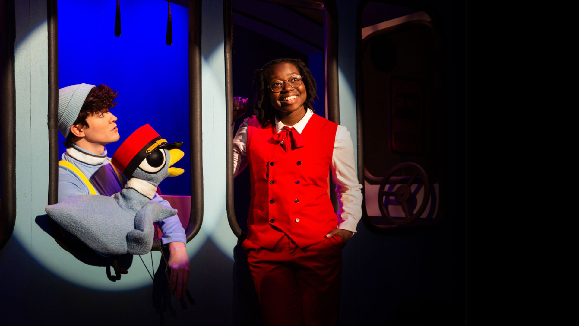 A man with a pigeon puppet talking to a woman through a window