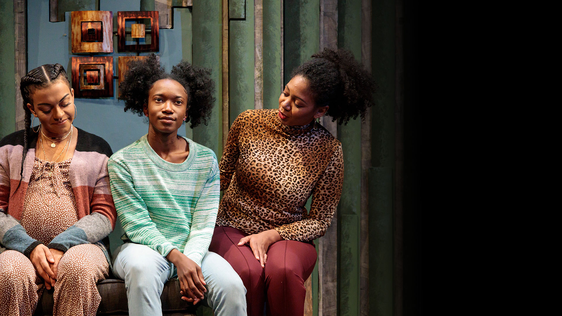 Three people sitting on couch, one is pregnant